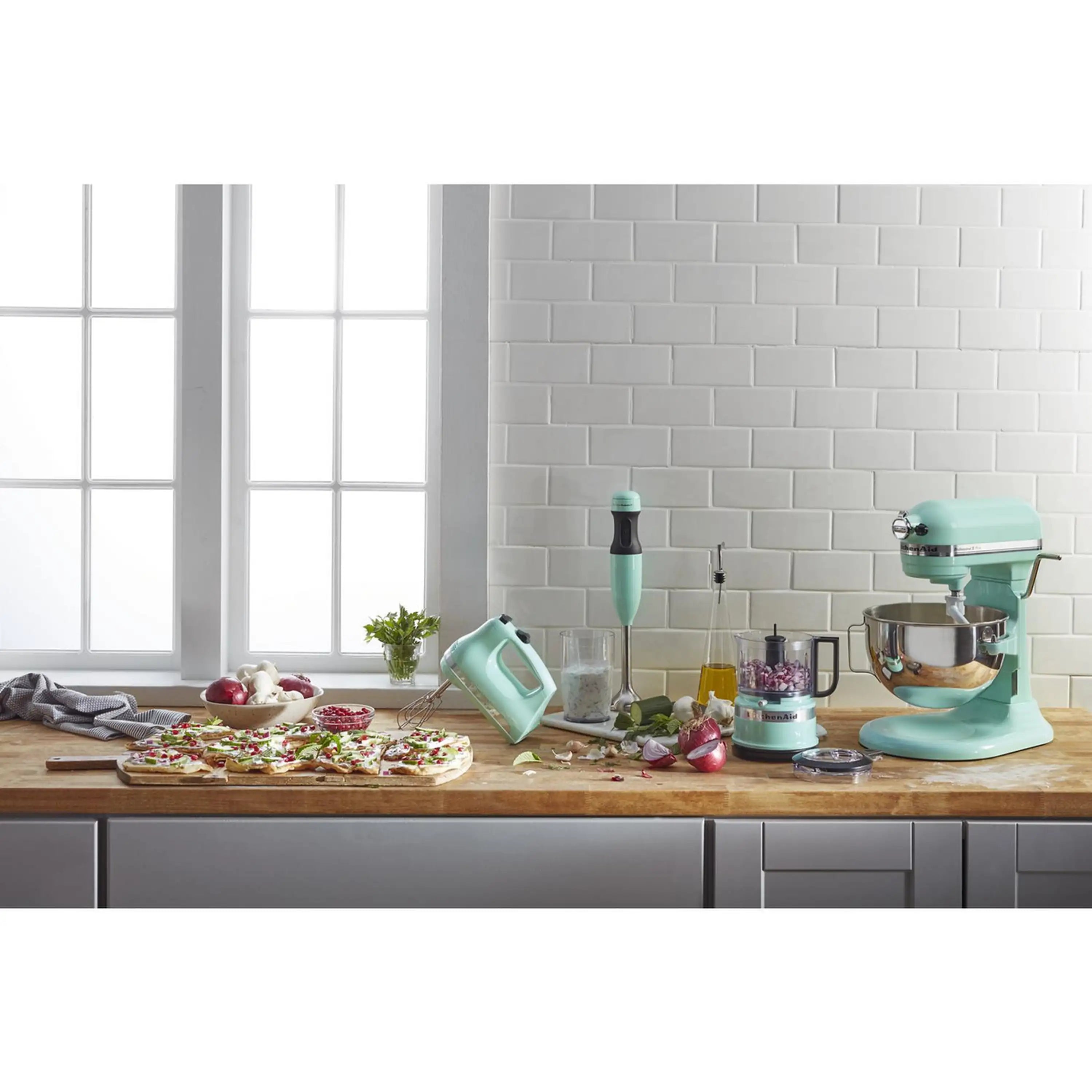 Ice-colored KitchenAid hand mixer on kitchen counter with beaters and matching attachments