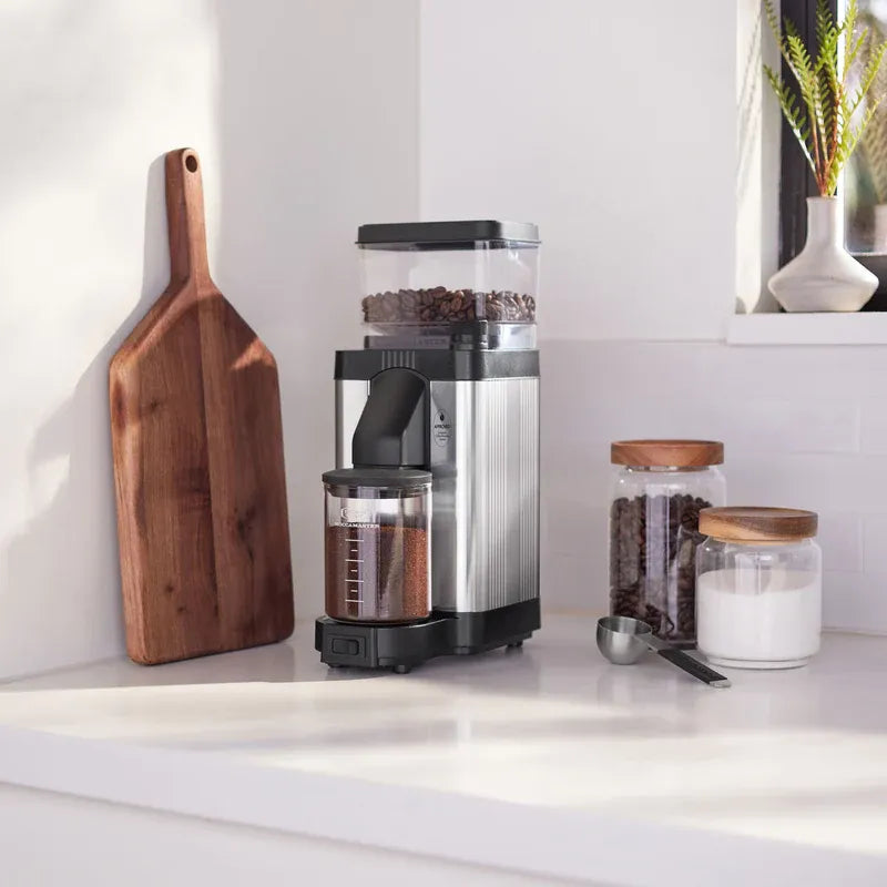 Polished silver burr grinder with black side chute and glass grounds bin