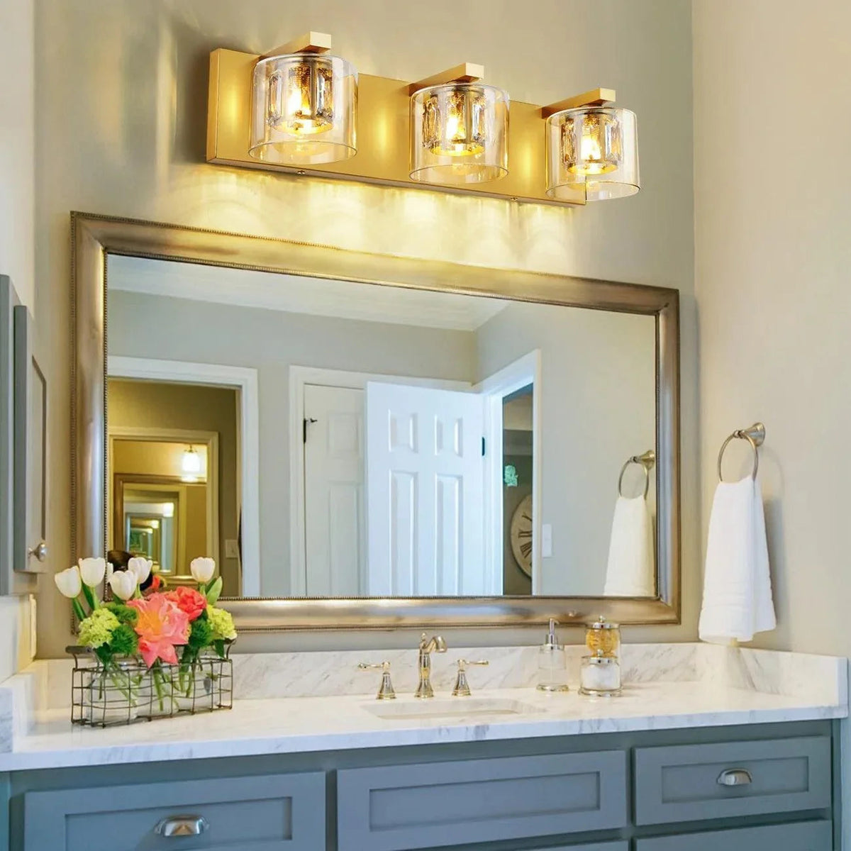 Wall-mounted 3-light vanity light with clear glass shades and gold backplate