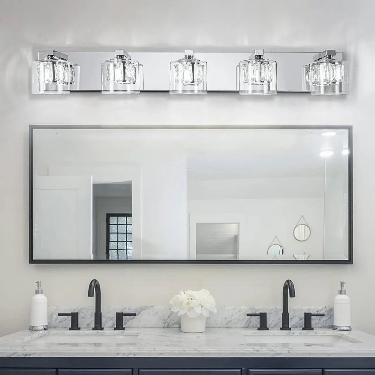 Chrome 5-light vanity light over wide mirror above sinks, clear glass shades aligned.