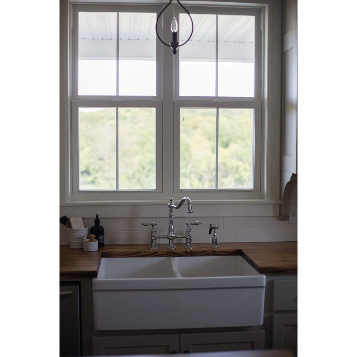 Polished chrome bridge kitchen faucet mounted over a white sink