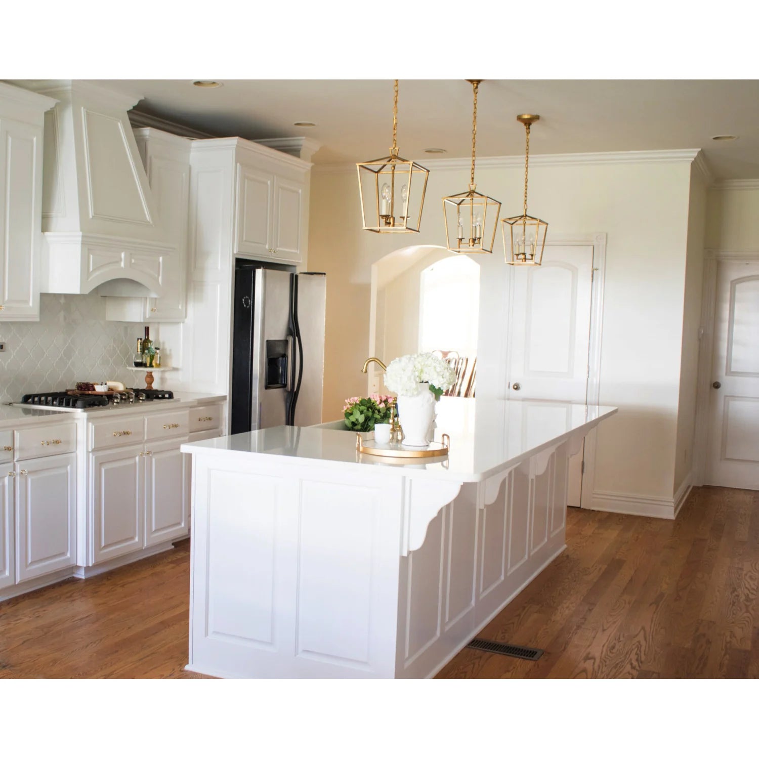 Polished brass bridge kitchen faucet with side sprayer on white countertop