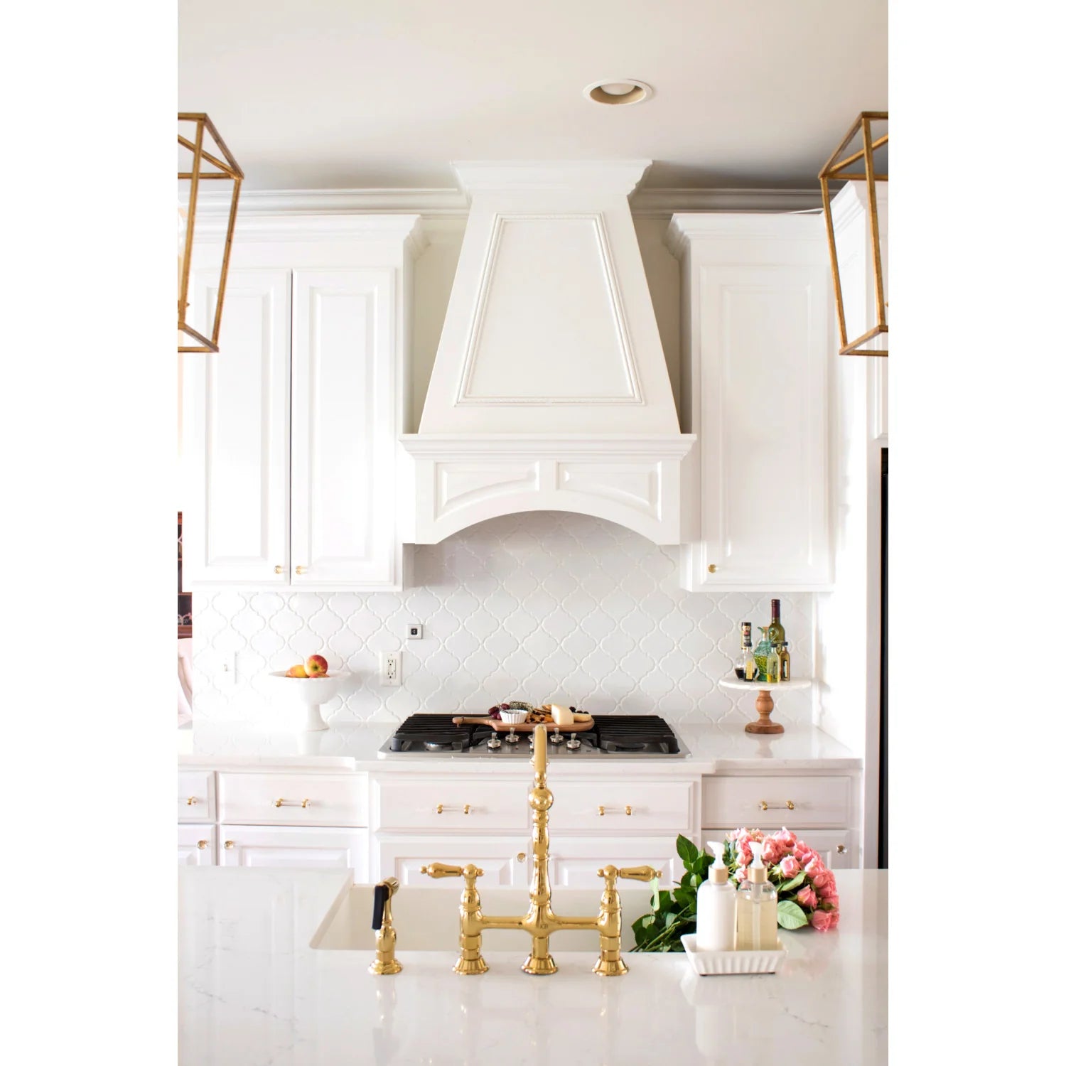 Polished brass bridge kitchen faucet with two handles and side sprayer on sink