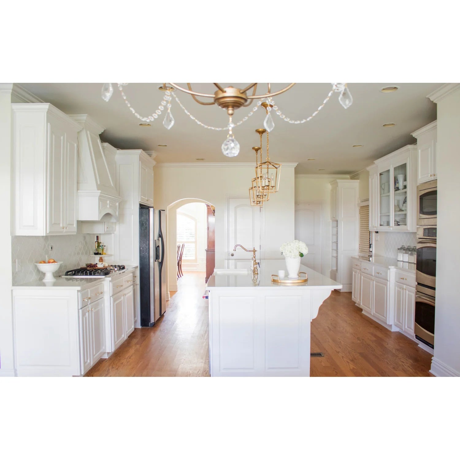 Polished brass bridge faucet with side sprayer over white island countertop