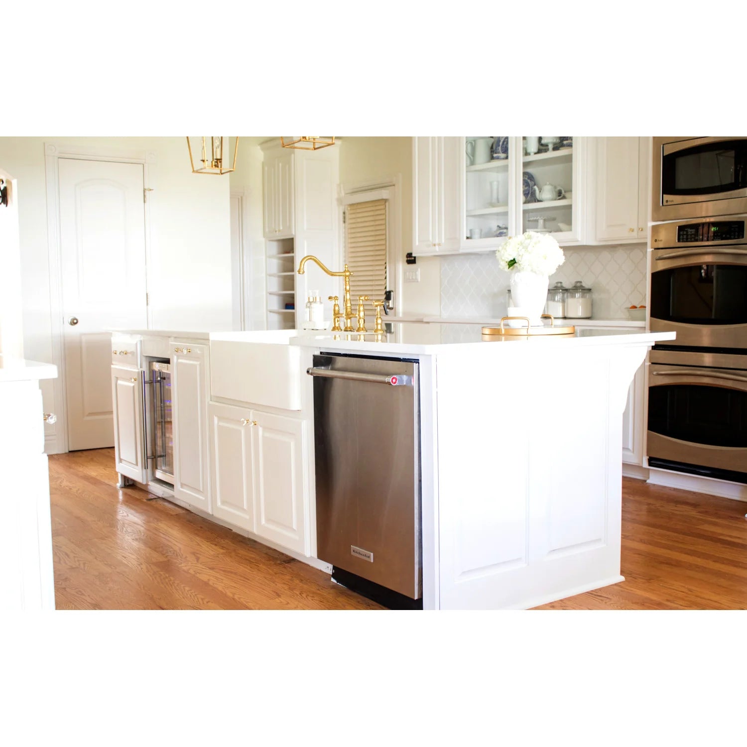 Polished brass bridge kitchen faucet installed on white kitchen counter