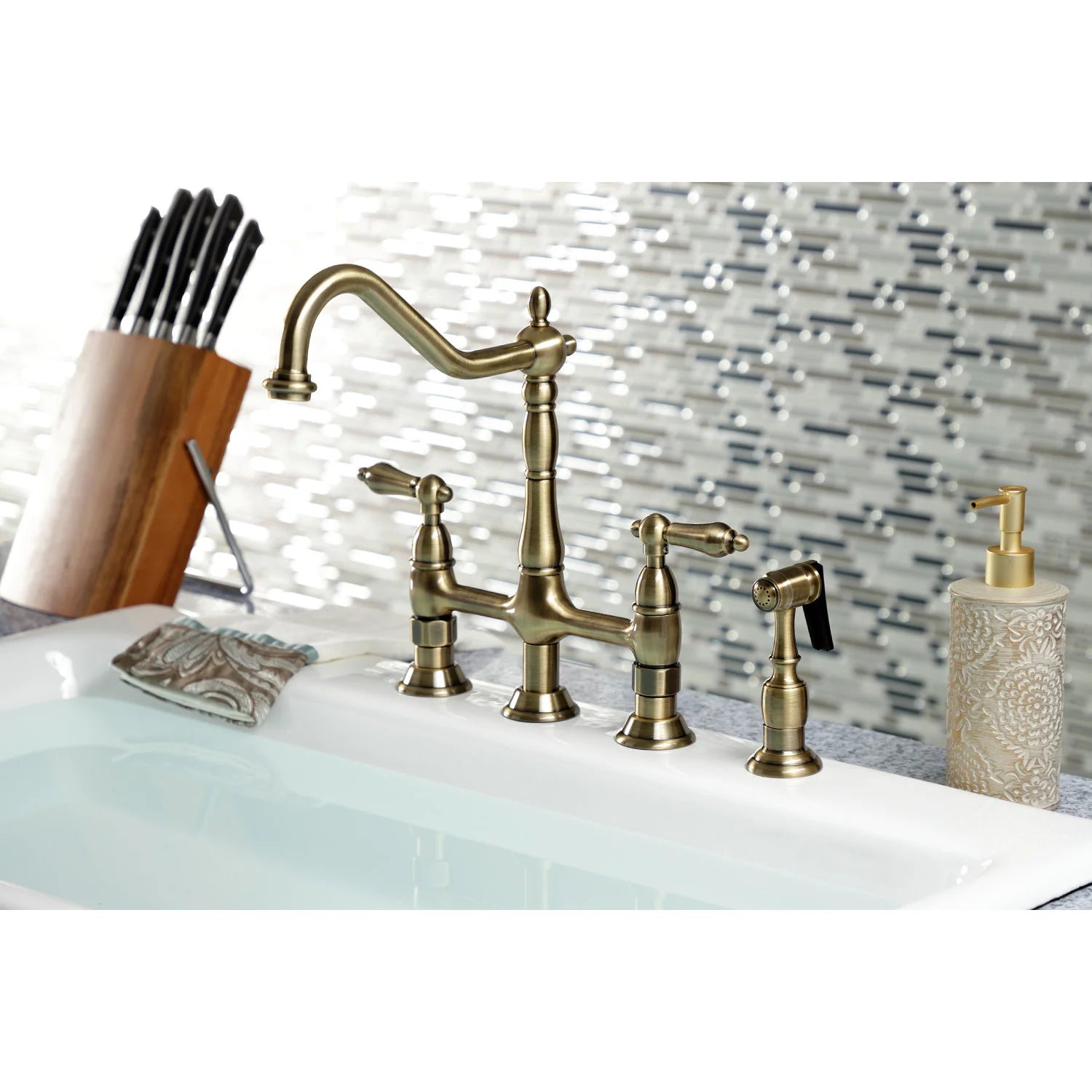 Antique brass bridge kitchen faucet with side sprayer on white sink