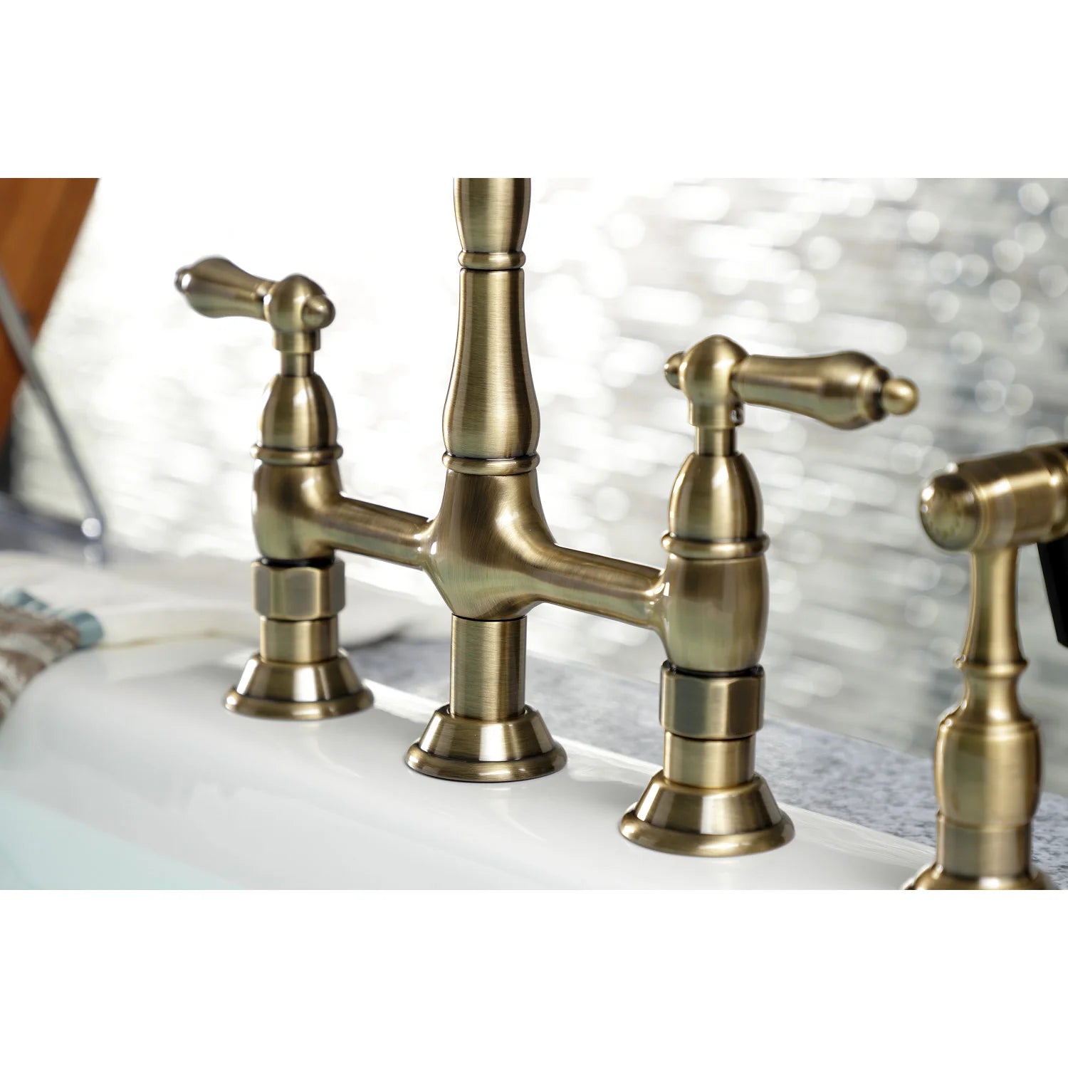 Antique brass bridge kitchen faucet with side sprayer and sculpted control knobs