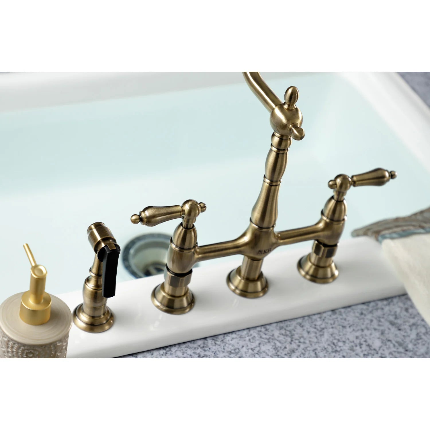 Antique brass bridge kitchen faucet and side sprayer on white sink
