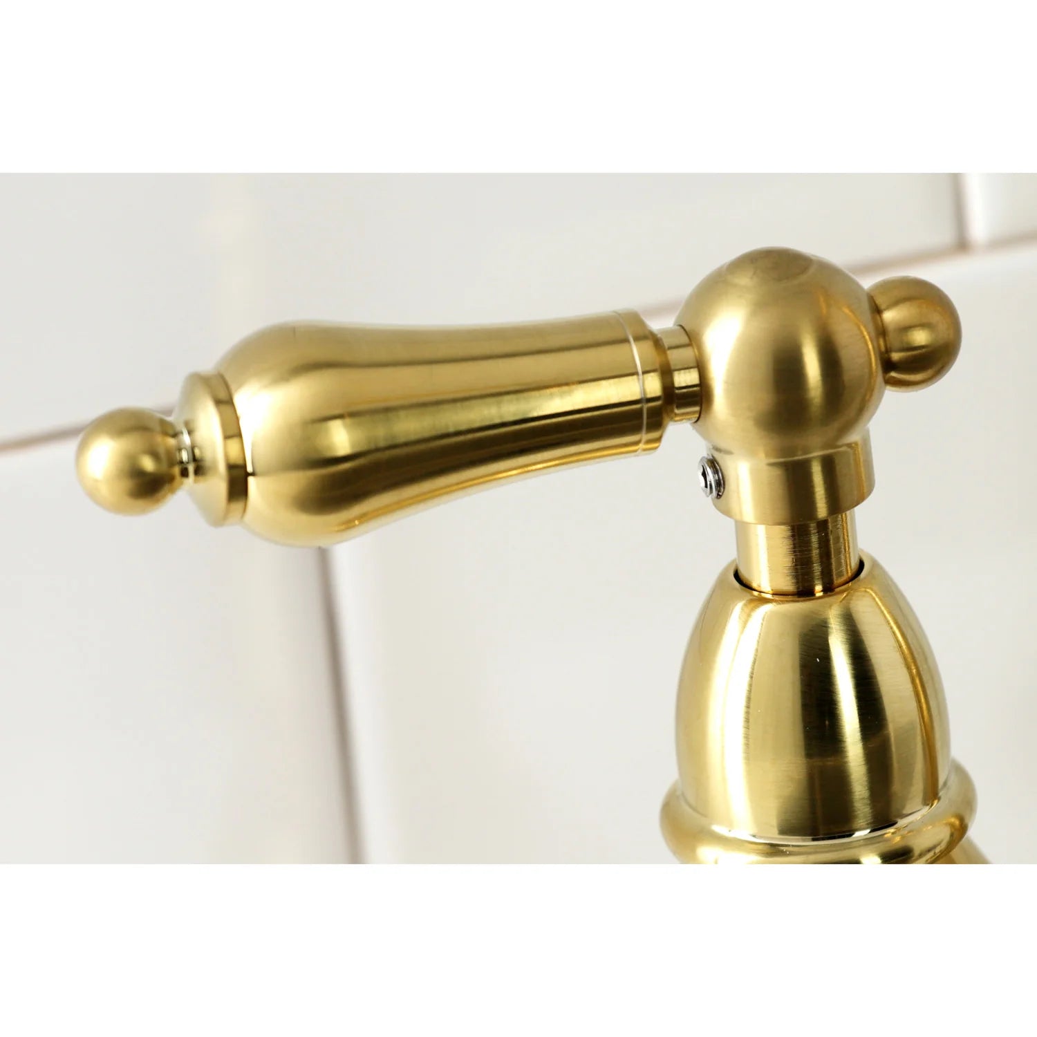 Close-up of brushed brass sprayer arm and handle connection
