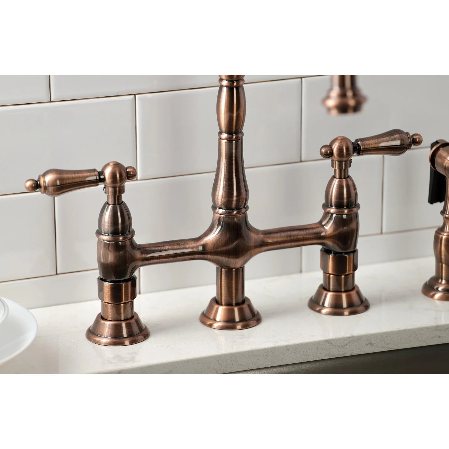 Antique copper bridge faucet with side sprayer and central spout base on sink
