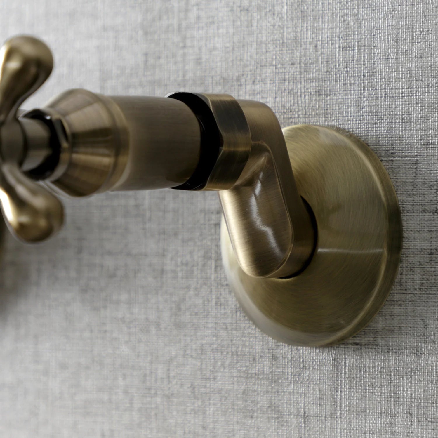 Antique brass wall-mount faucet with round escutcheon and black inlet cover