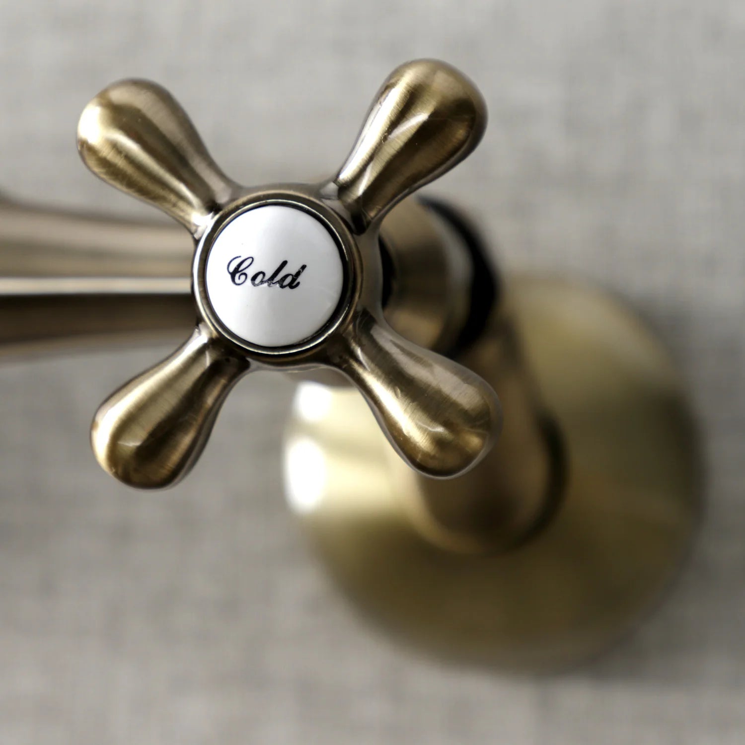Antique brass handle with Cold label on double-handle wall-mount faucet