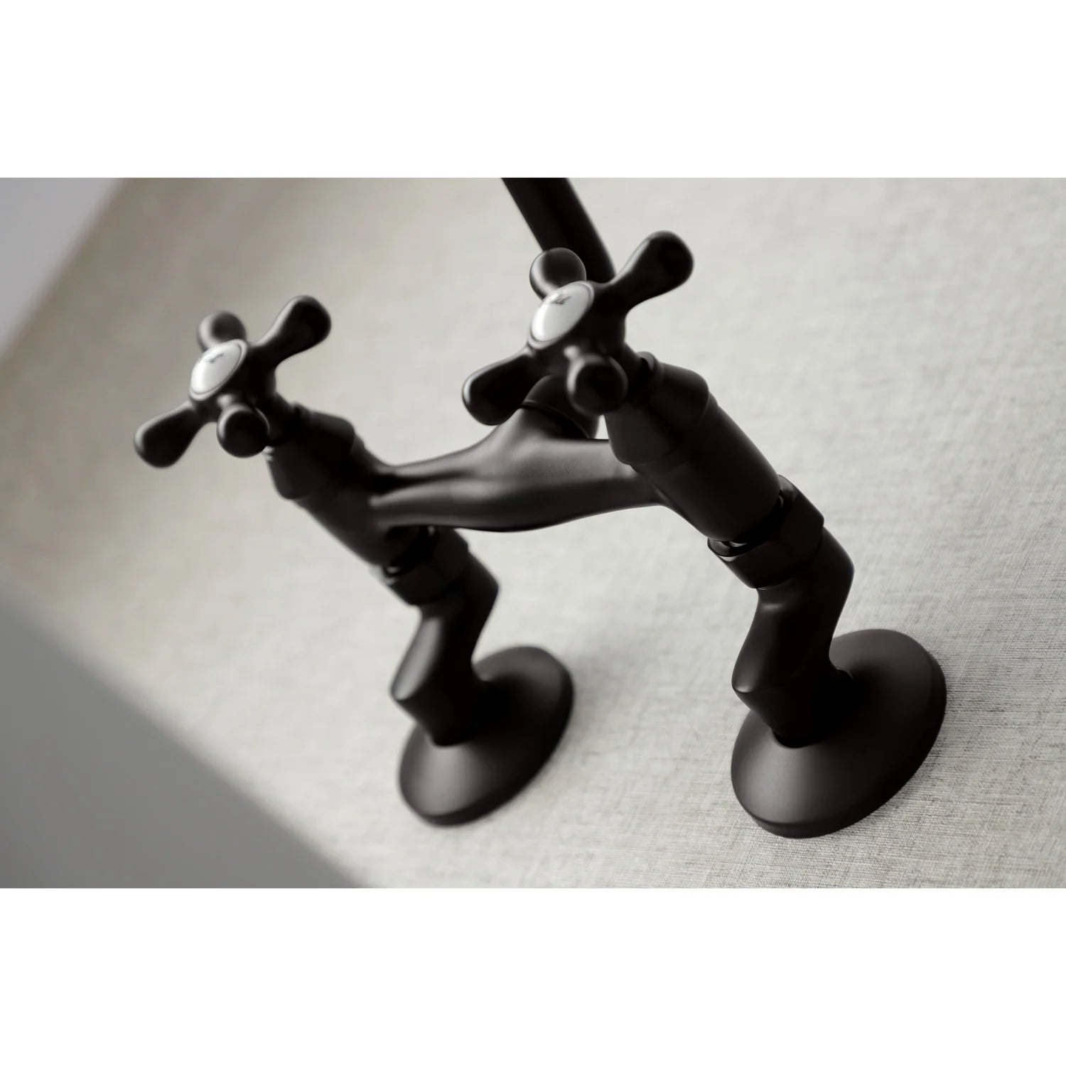 Oil-rubbed bronze bridge faucet close-up with dual cross handles and white hot/cold caps