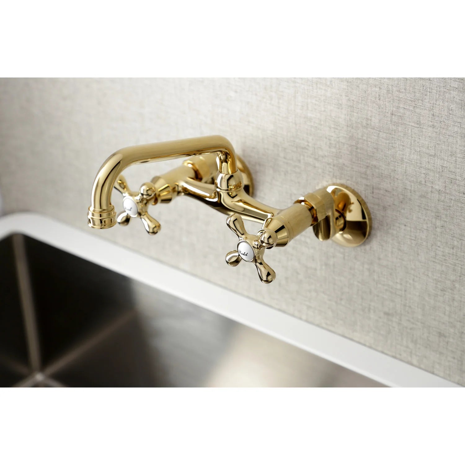 Polished brass wall-mount bridge faucet with double cross handles above sink