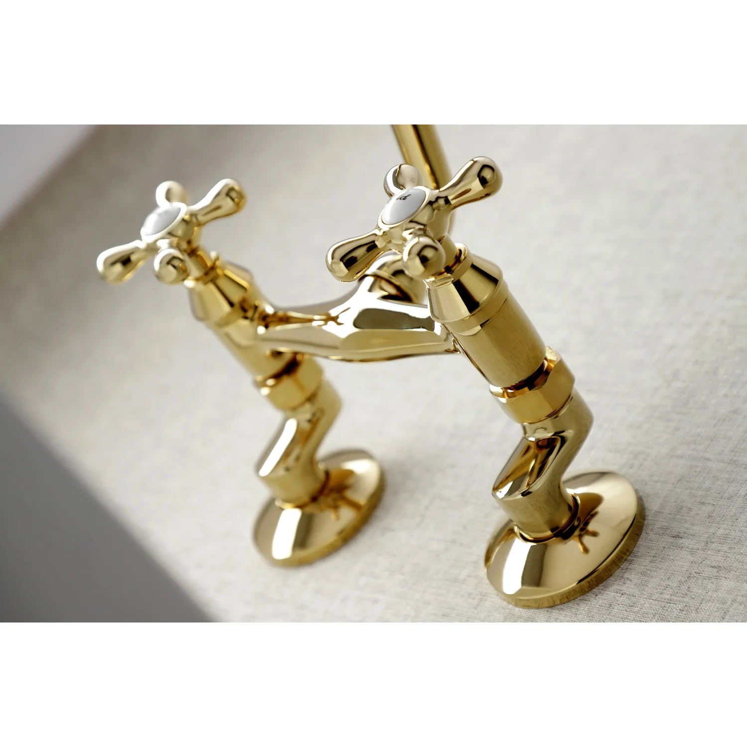 Polished brass bridge faucet with two cross handles, deck plate, and curved spout