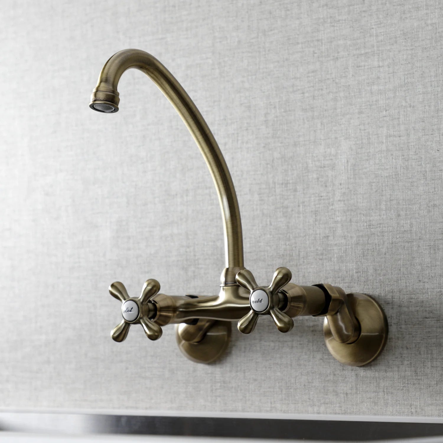 Antique brass bridge kitchen faucet with curved spout and two cross handles, wall mount