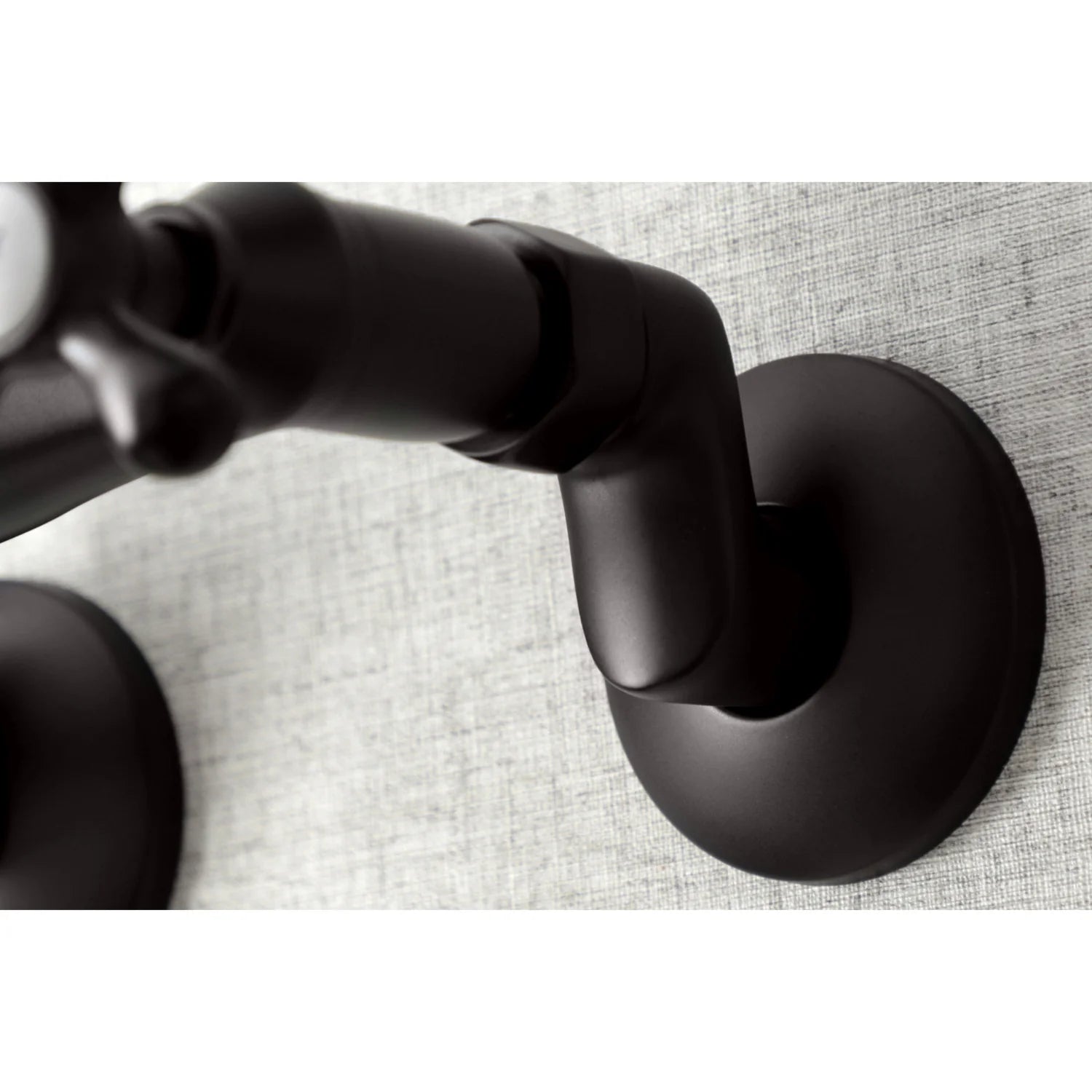 Oil-rubbed bronze faucet handle ends and mounting base detail on a wall-mount bridge faucet