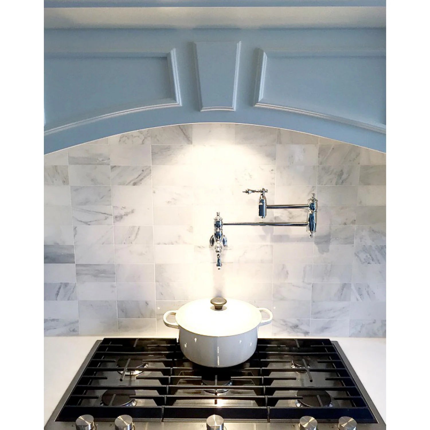 Polished chrome pot filler faucet with two arms on a tiled backsplash