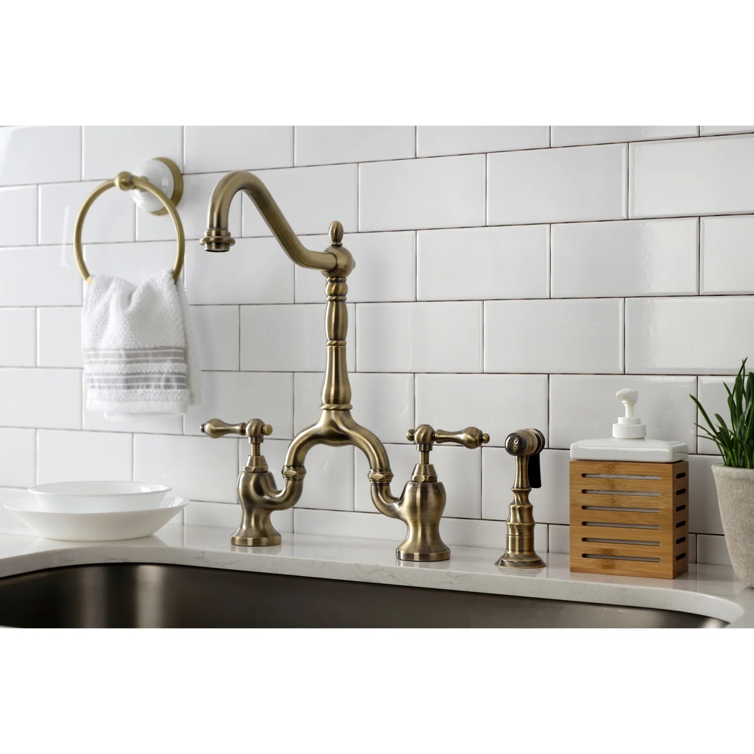 Antique brass bridge kitchen faucet with side sprayer and curved spout in kitchen