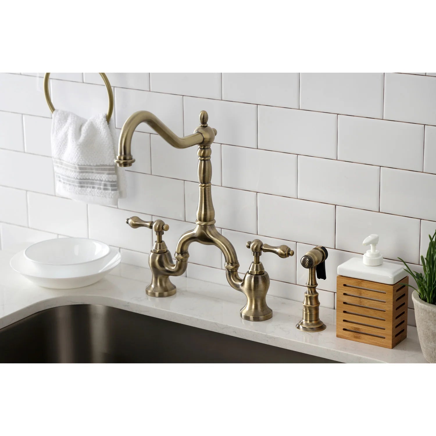 Antique brass bridge kitchen faucet with side sprayer mounted on countertop