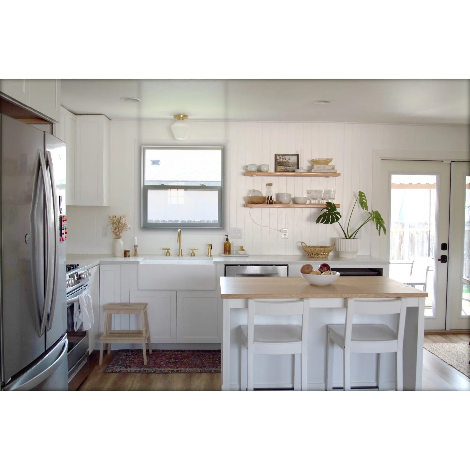 Brushed brass sink faucet with dual handles and arched spout in bright kitchen