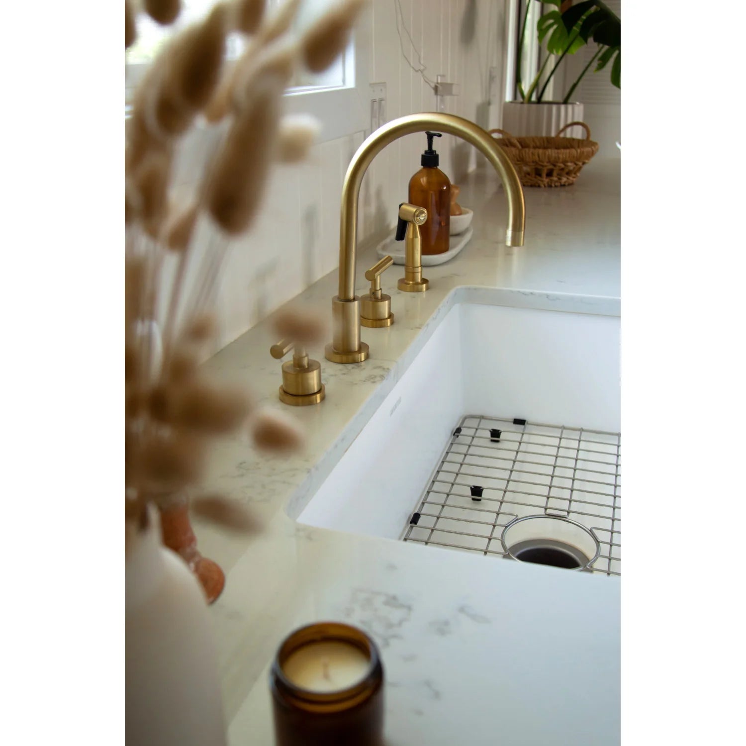 Brushed brass arched kitchen faucet and handles over white sink basin