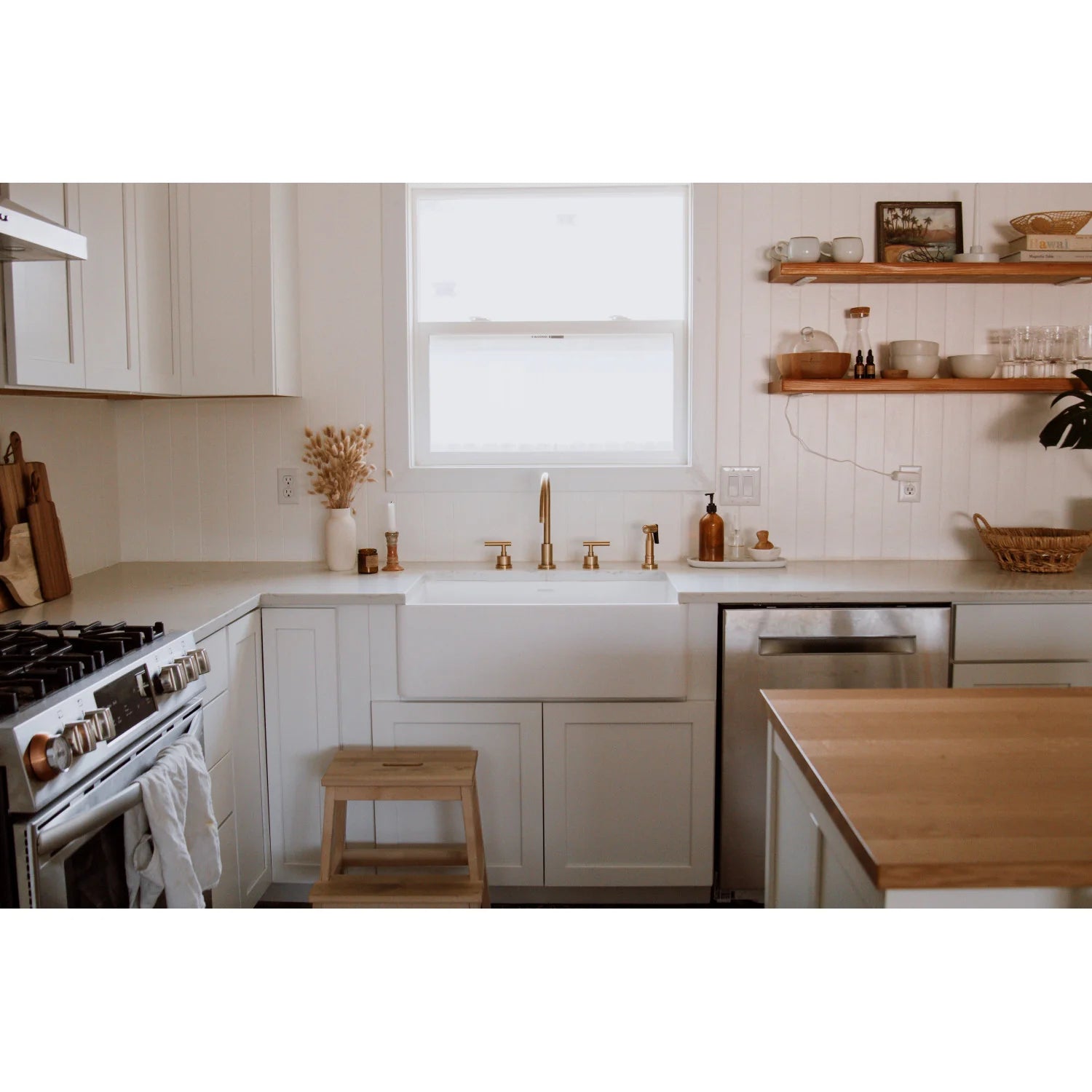 Brushed brass kitchen faucet set on white countertop beside double sink area