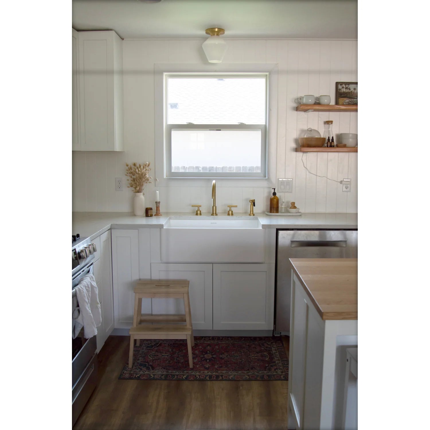 Brushed brass kitchen sink faucet with widespread handles in modern white kitchen