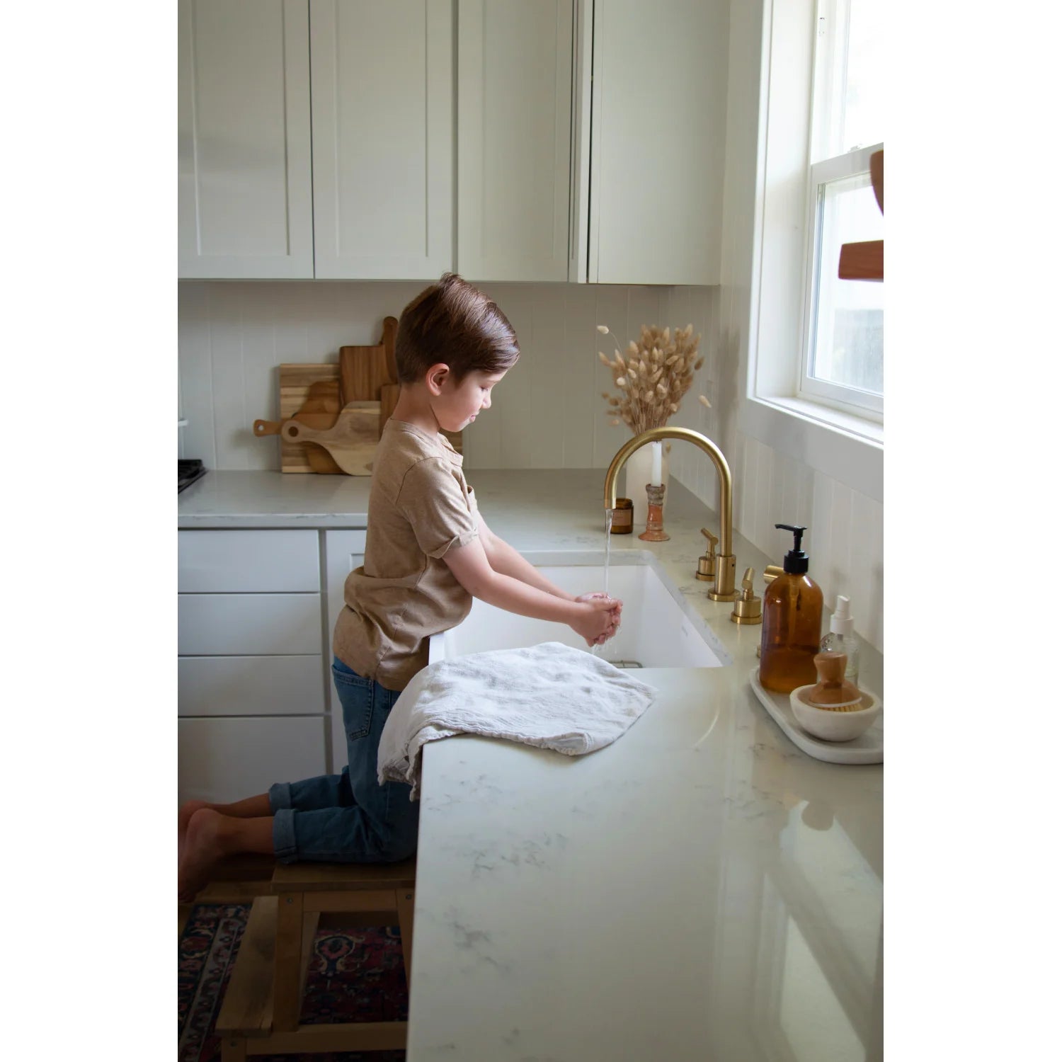 Brushed brass kitchen faucet with two handles and pull-down sprayer in use