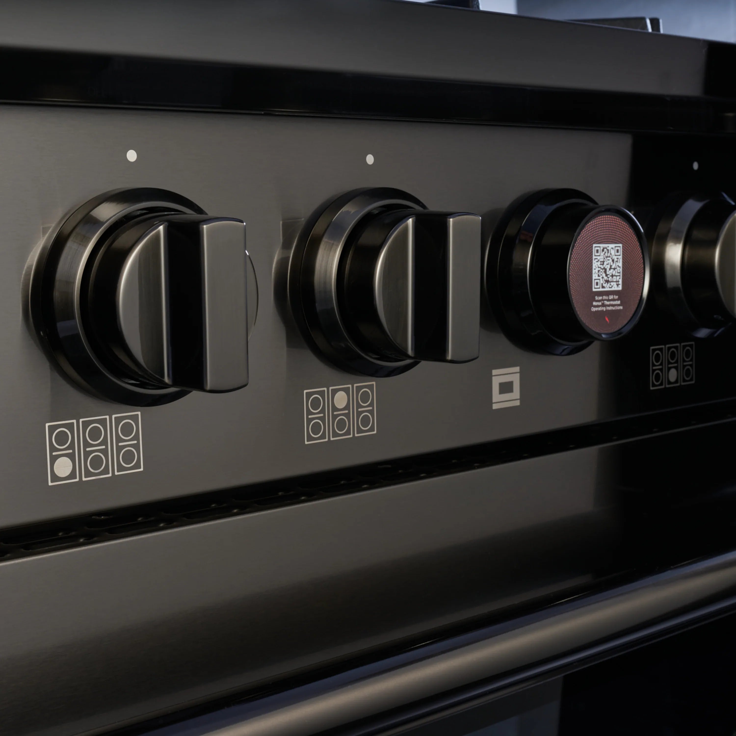 Dual-fuel range control panel with black knobs and stainless steel switch area