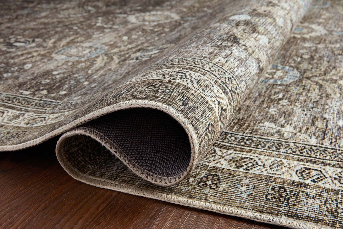 Traditional area rug with rolled edge showing textured pile and weave, antique gray pattern