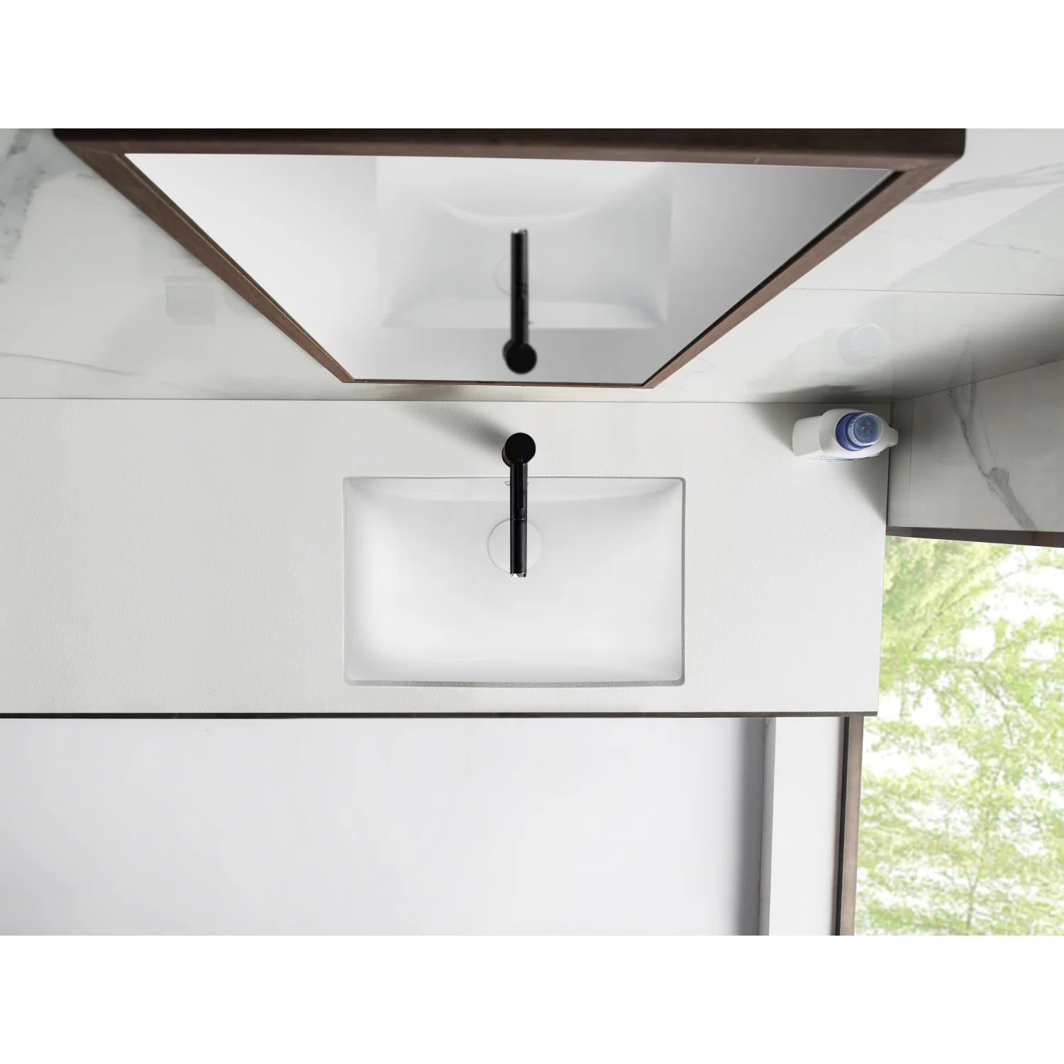 Installed white rectangular undermount bathroom sink with drain and overflow openings