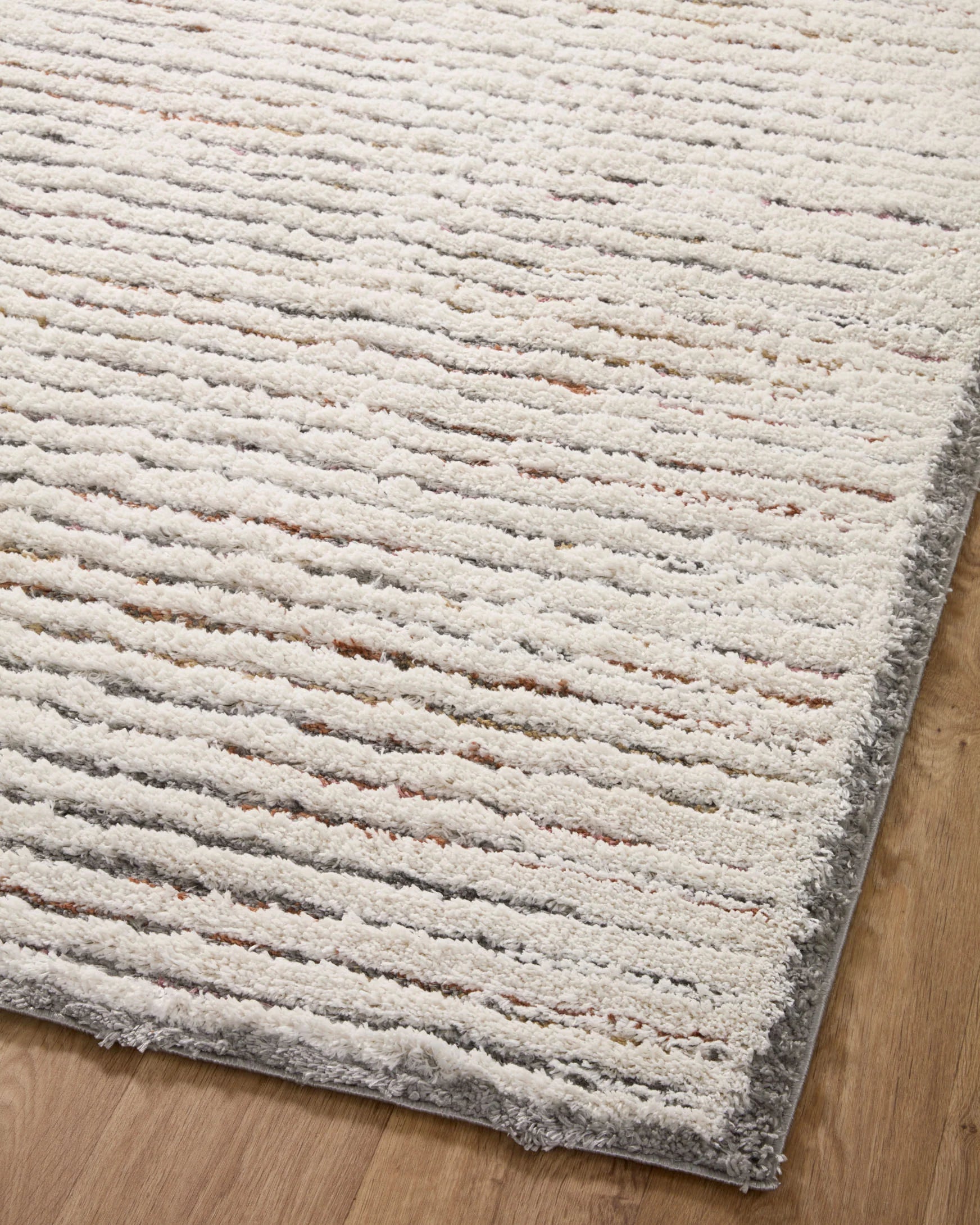 Ivory shag area rug close-up with horizontal ribbed texture and gray border
