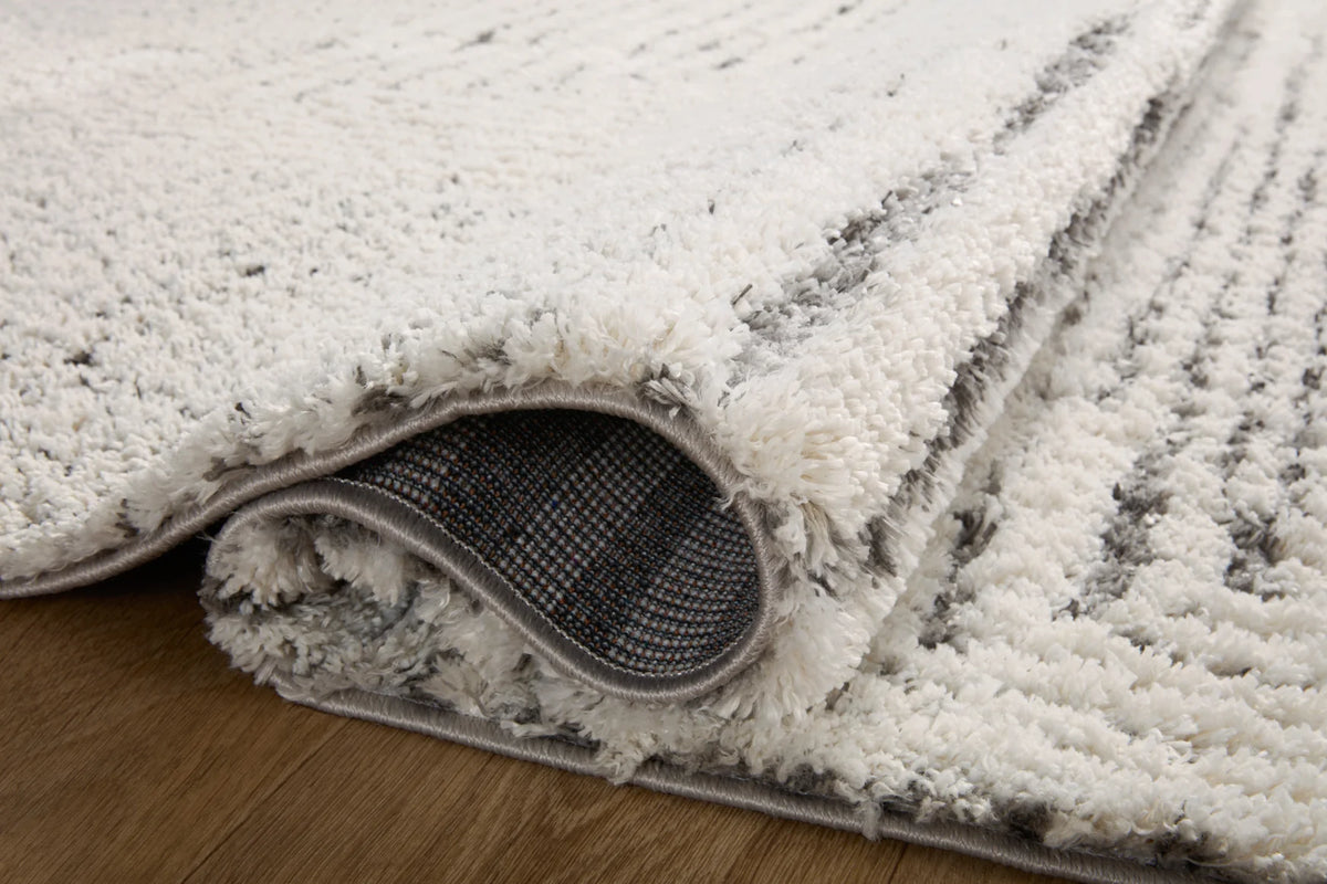 Shag rug corner with grey fabric backing and thick ivory loop pile