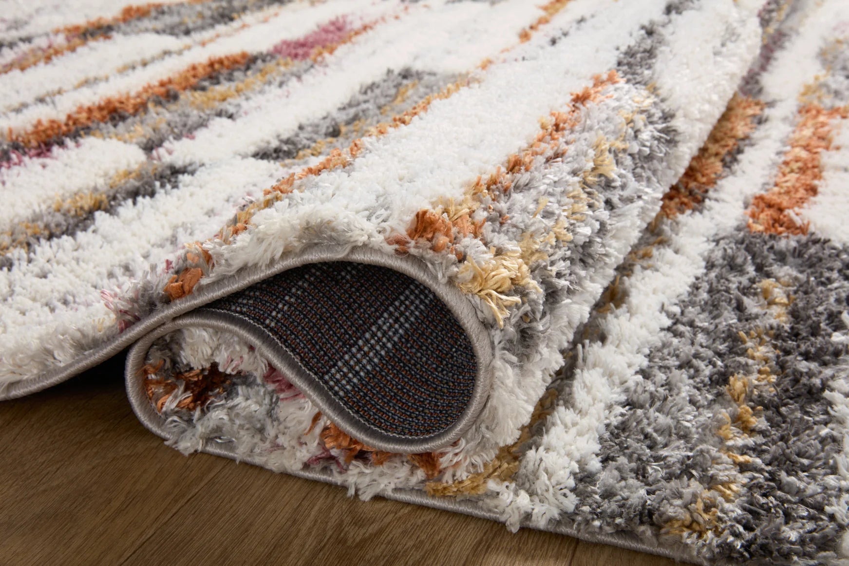 Shag area rug corner close-up, ivory and gray with orange and rose stripes