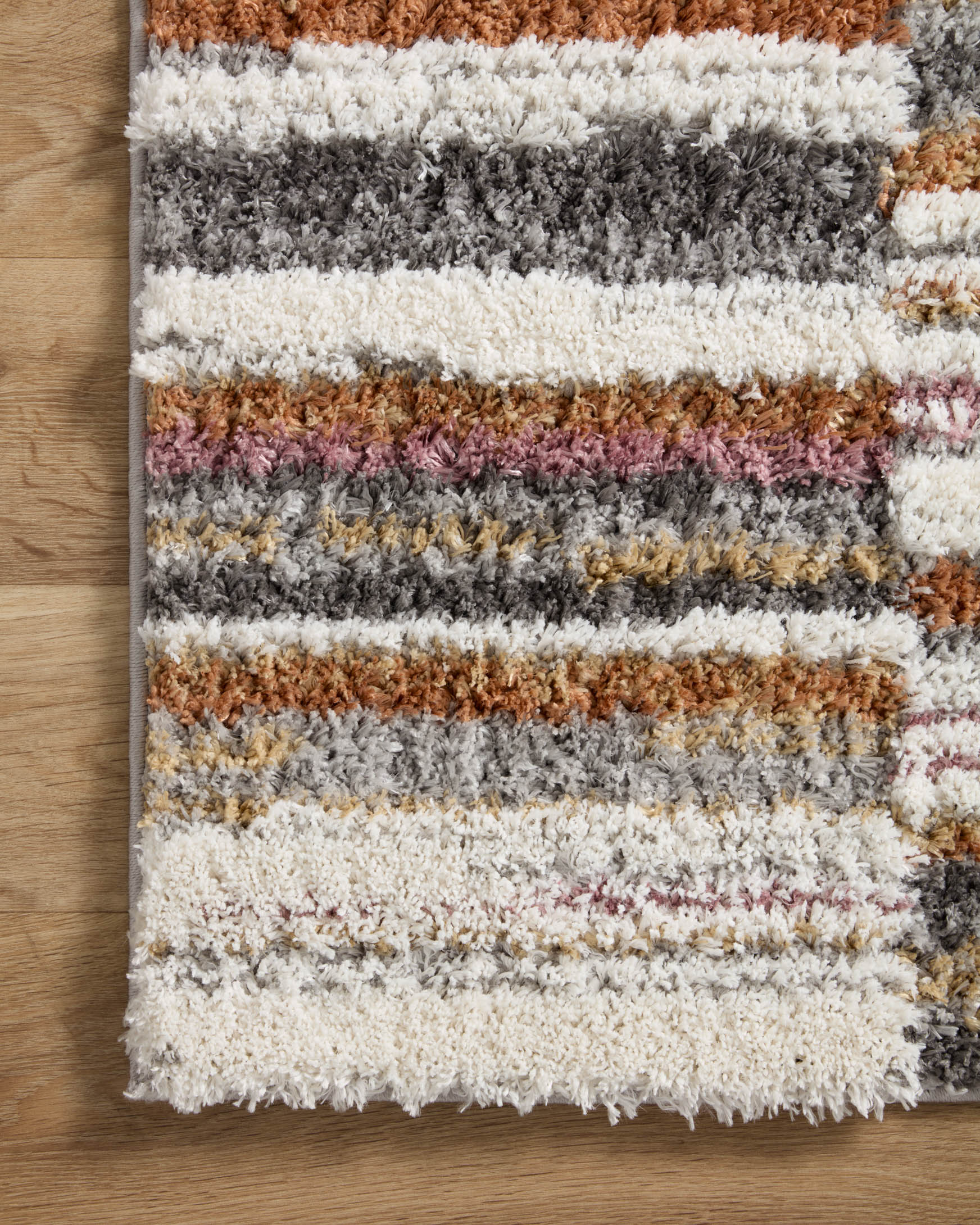 Top view of striped shag runner rug with ivory, charcoal, gray, and warm orange bands