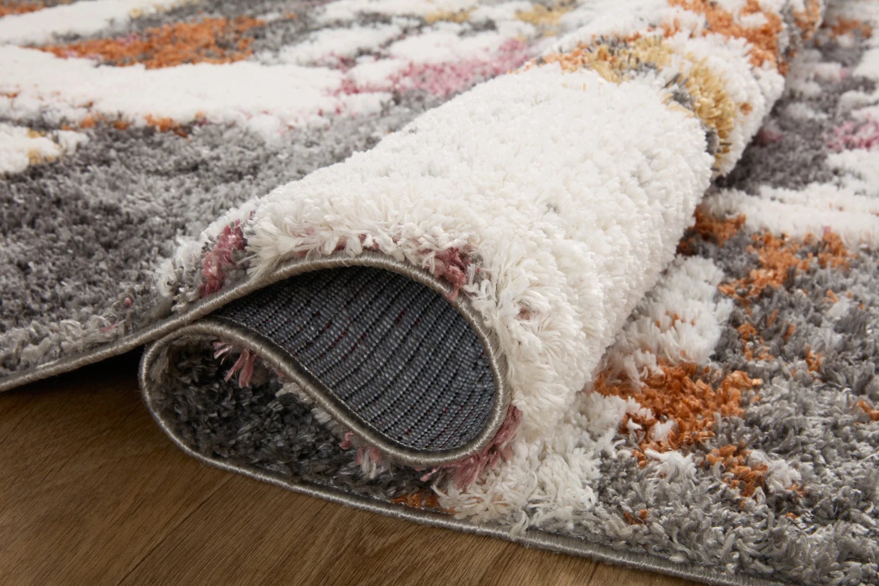 Shag area rug corner detail with cream pile and dark grey backing