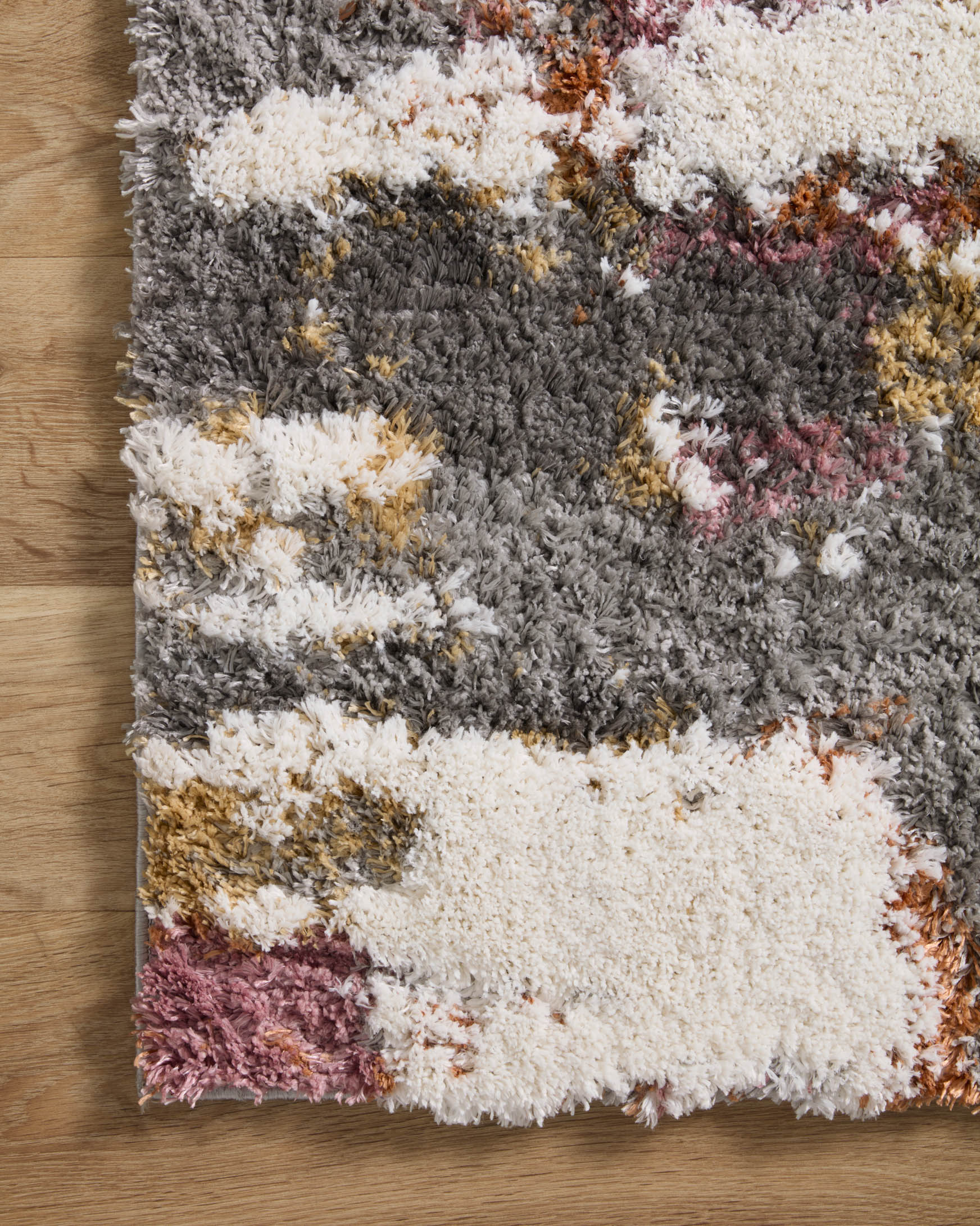 Close-up of shag area rug texture with grey, cream, and muted orange and pink accents