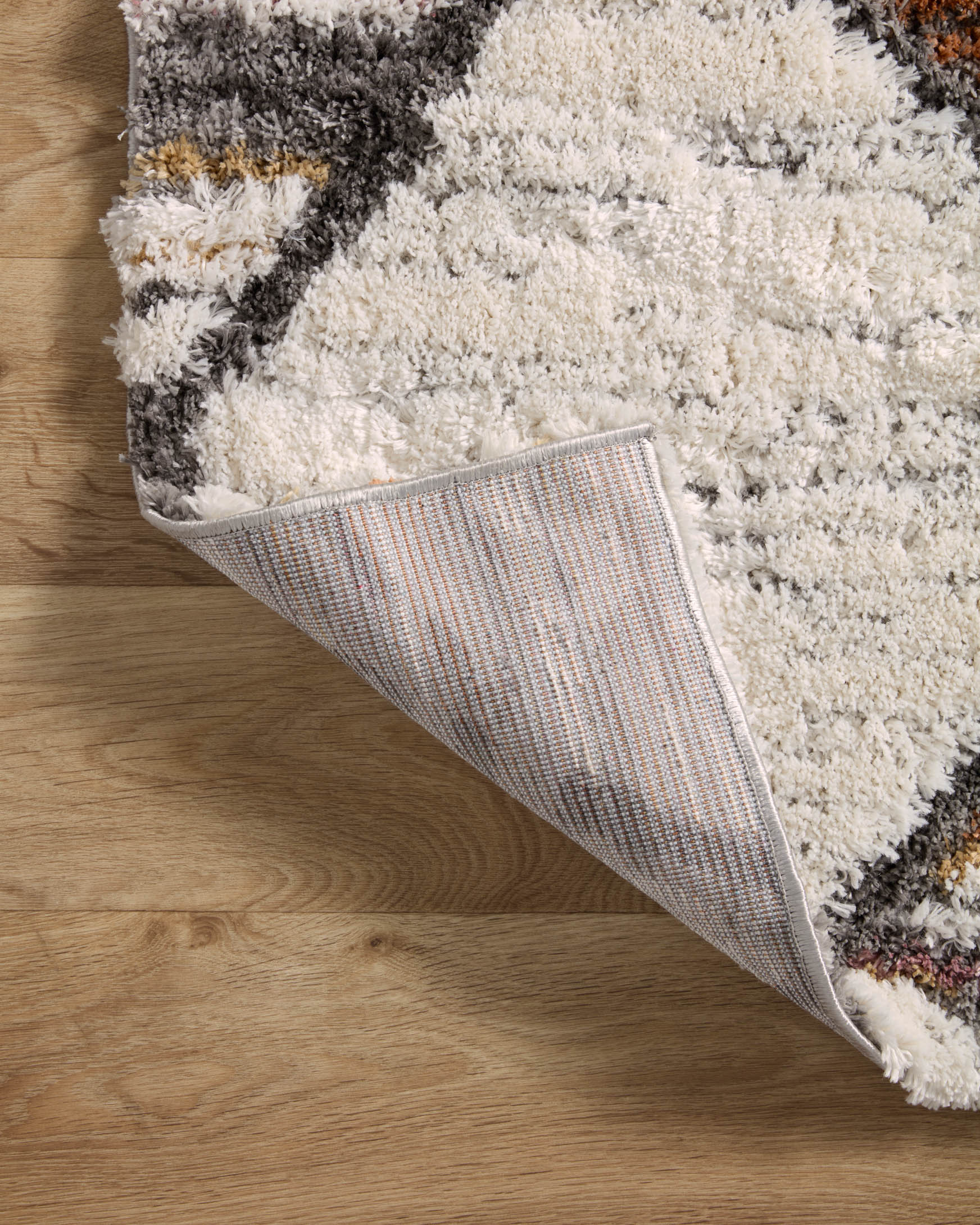 Shag runner rug edge with light gray backing visible along folded corner
