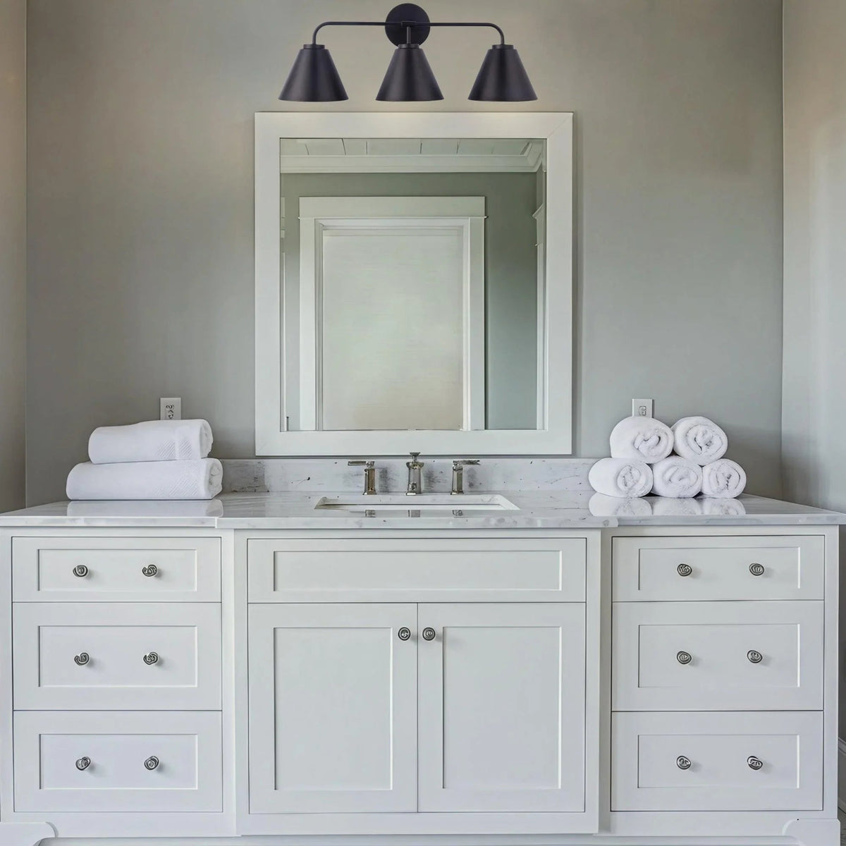 Black 3-light vanity light with three cone shades over a white vanity setup