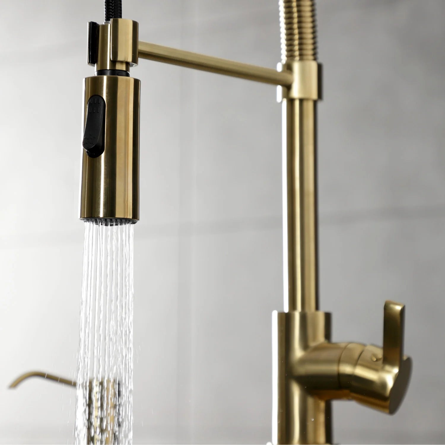 Brushed brass single-handle kitchen faucet with spray head and rising gooseneck spout