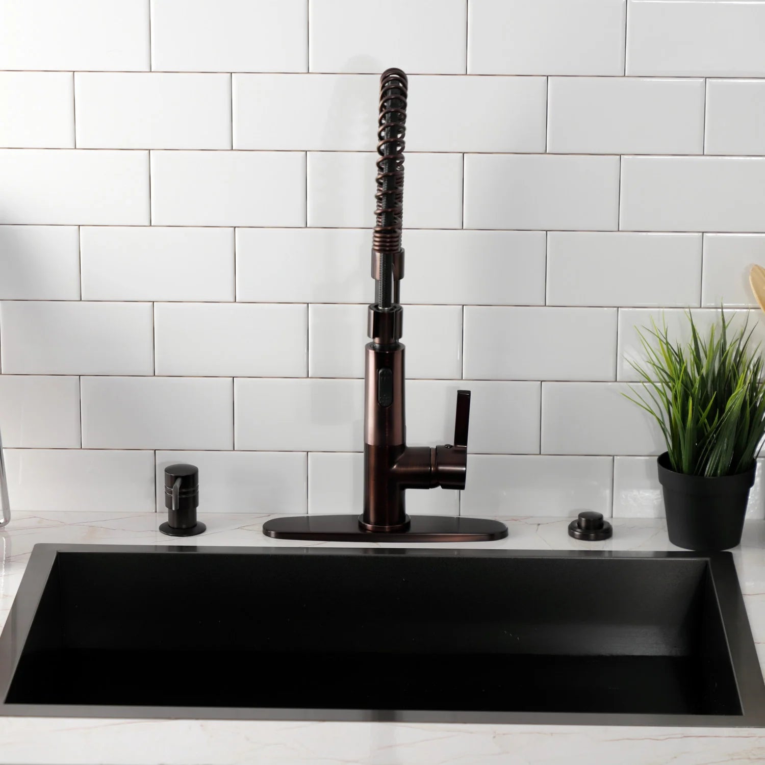 Oil-rubbed bronze deck-mount kitchen faucet centered on the sink with coiled hose