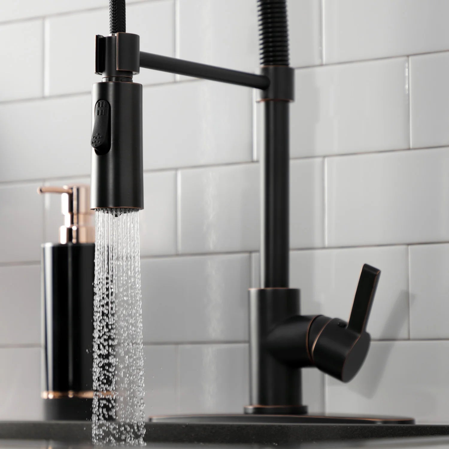 Matte black pull-down kitchen faucet pouring water from the spray head