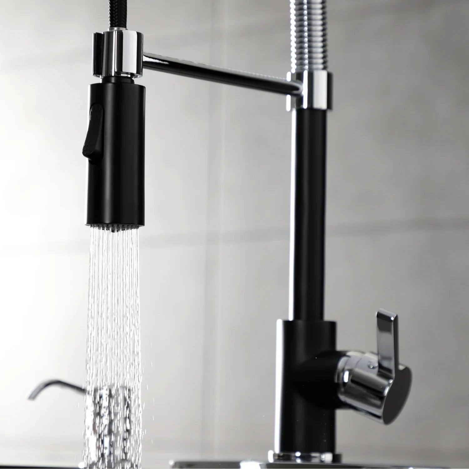 Matte black kitchen faucet delivering water spray from chrome shower head
