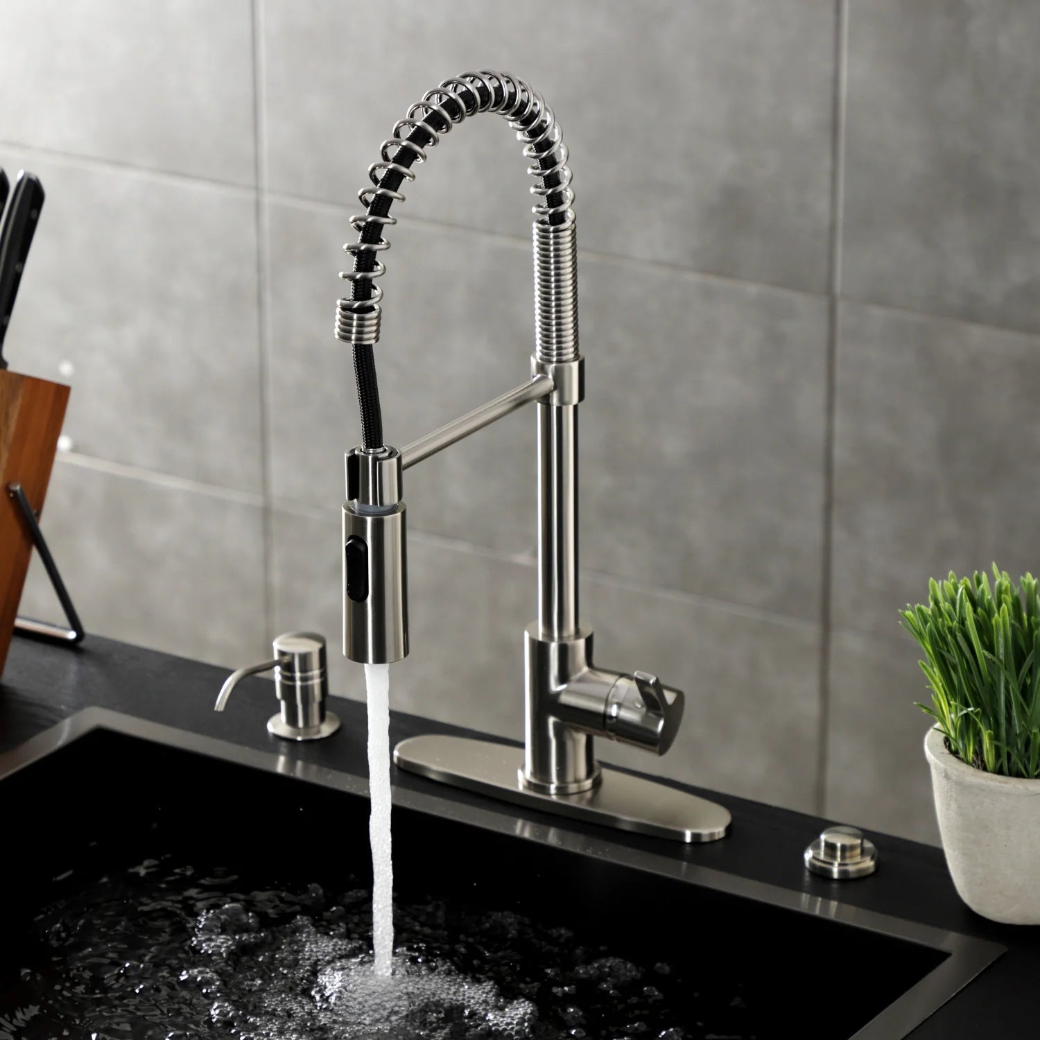 Brushed nickel deck-mount pre-rinse faucet with water stream over black sink