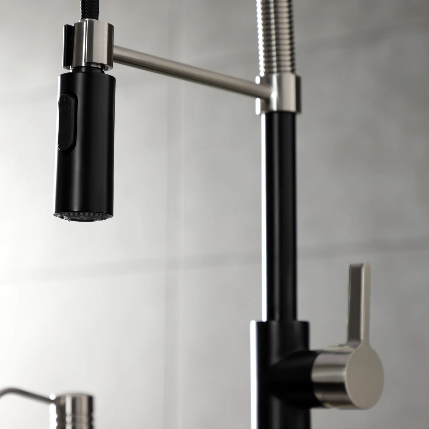 Matte black single-handle pre-rinse faucet with brushed nickel spout, hose, and water stream