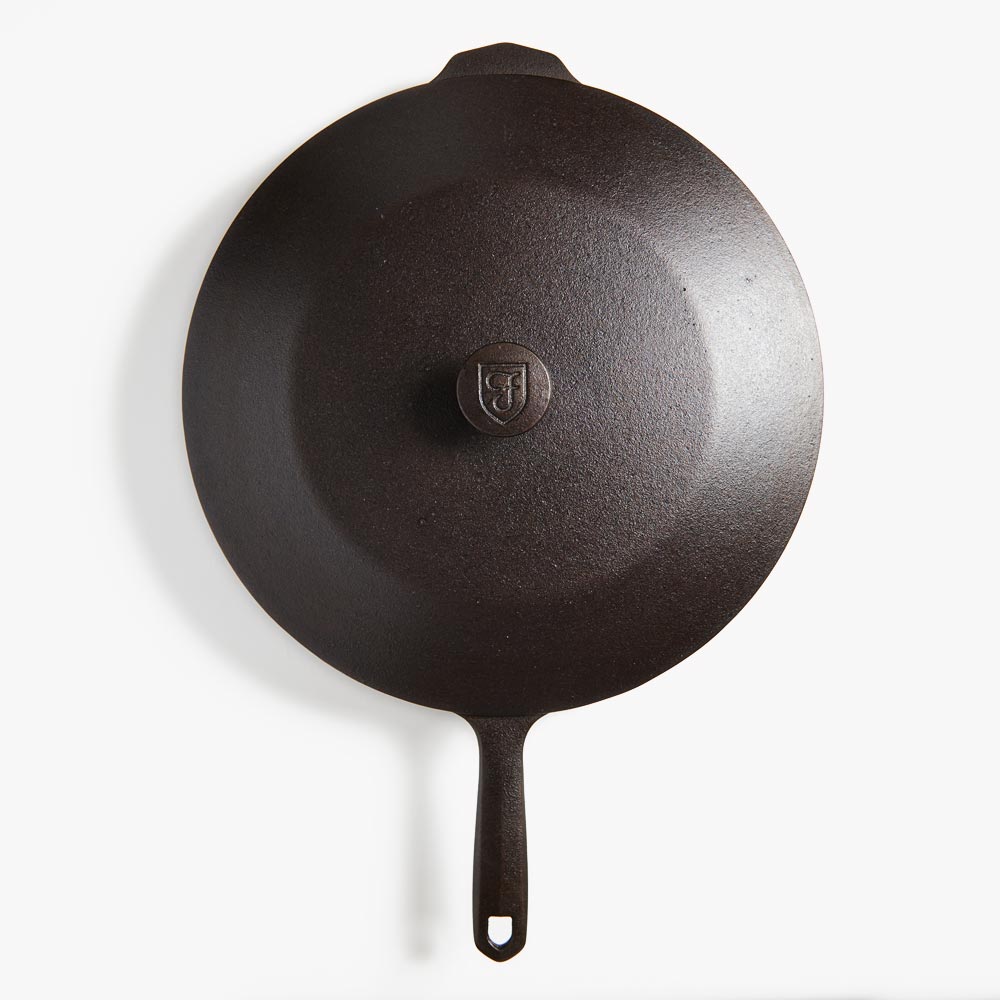 Dark cast-iron skillet with lid knob and loop handle