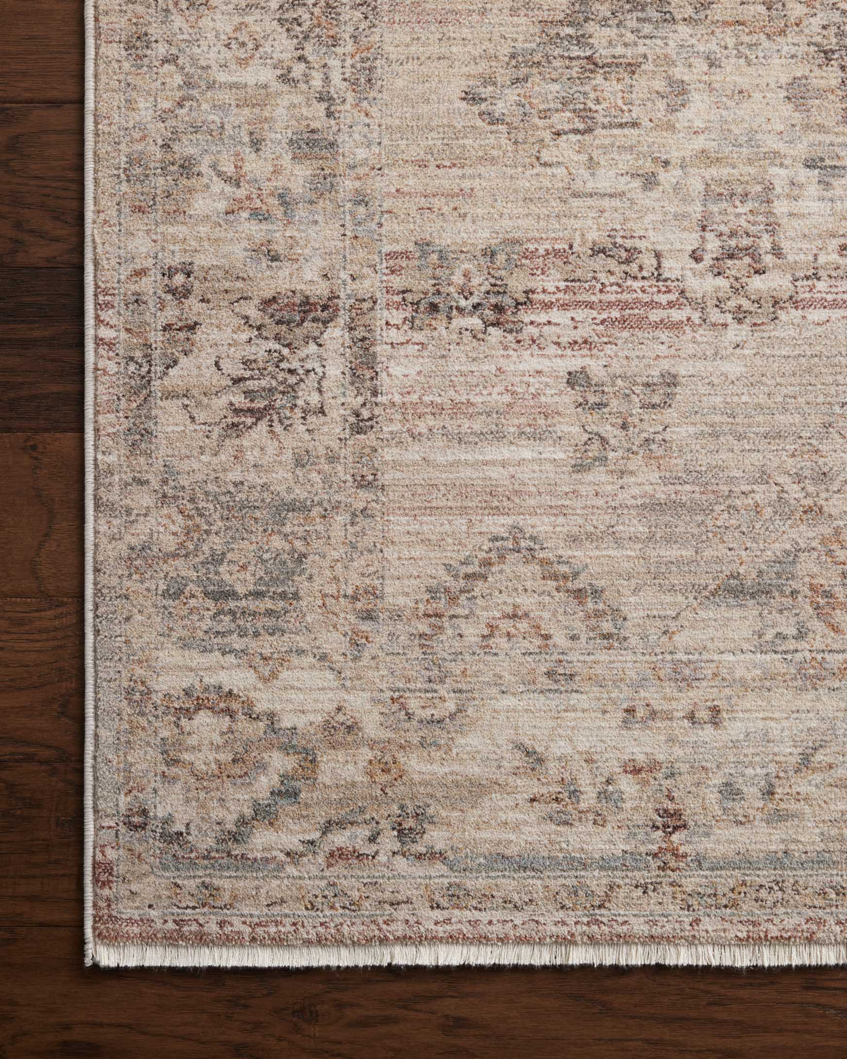 Blush and dove area rug close-up with distressed medallion pattern and fringed border.