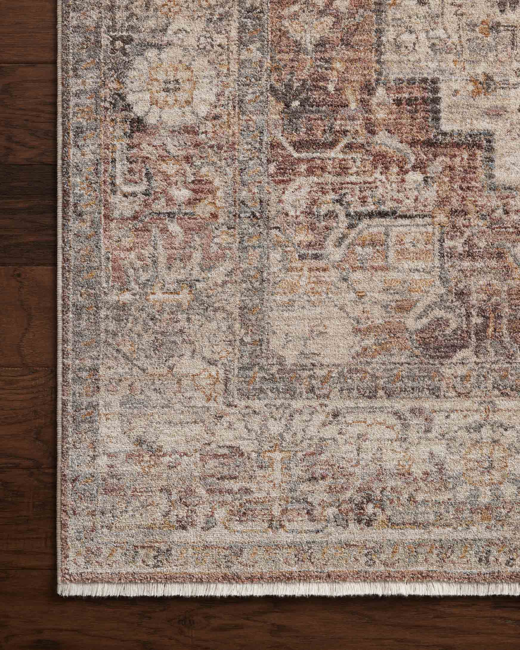 Accent rug corner with textured distressed motifs in muted berry, stone, and gray.