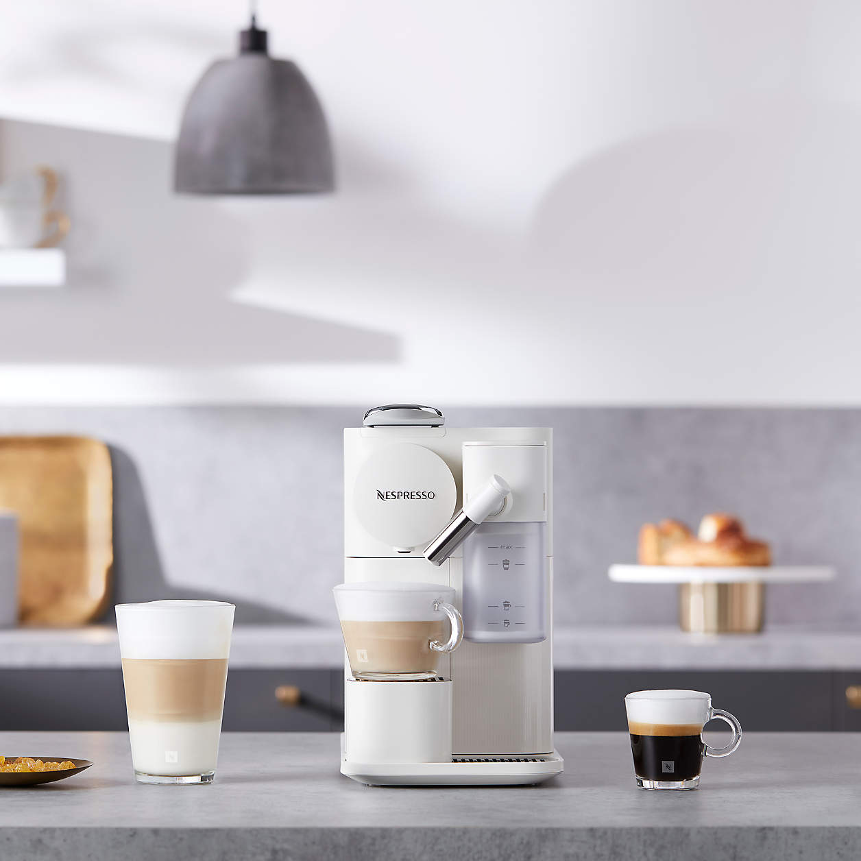 White Nespresso coffee machine with two cups and milk carafe visible